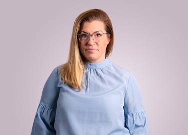 Woman in long blonde hari, with glasses and a light blue blouse