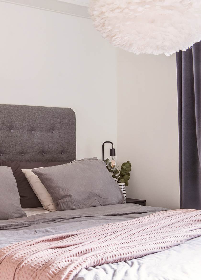 Bed with grey headboard and cushions