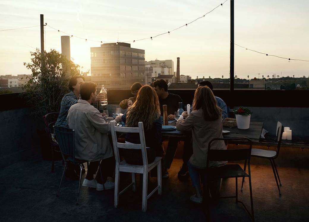 Friends having dinner on roof top in sunset