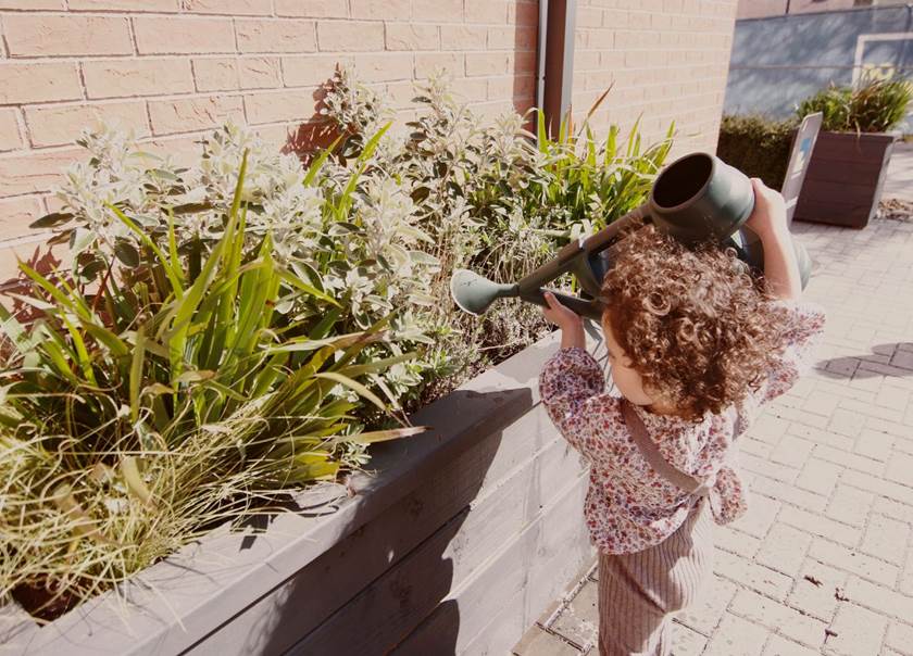 Little girl outside watering plants