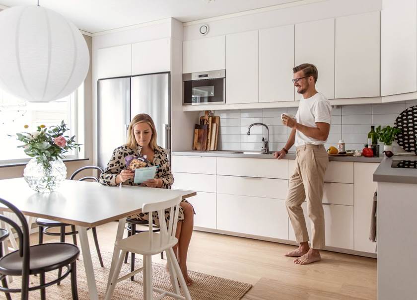 Lady sat at kitchen table and husband stood leaning on work top Lady sat at kitchen table and husband stood leaning on work top