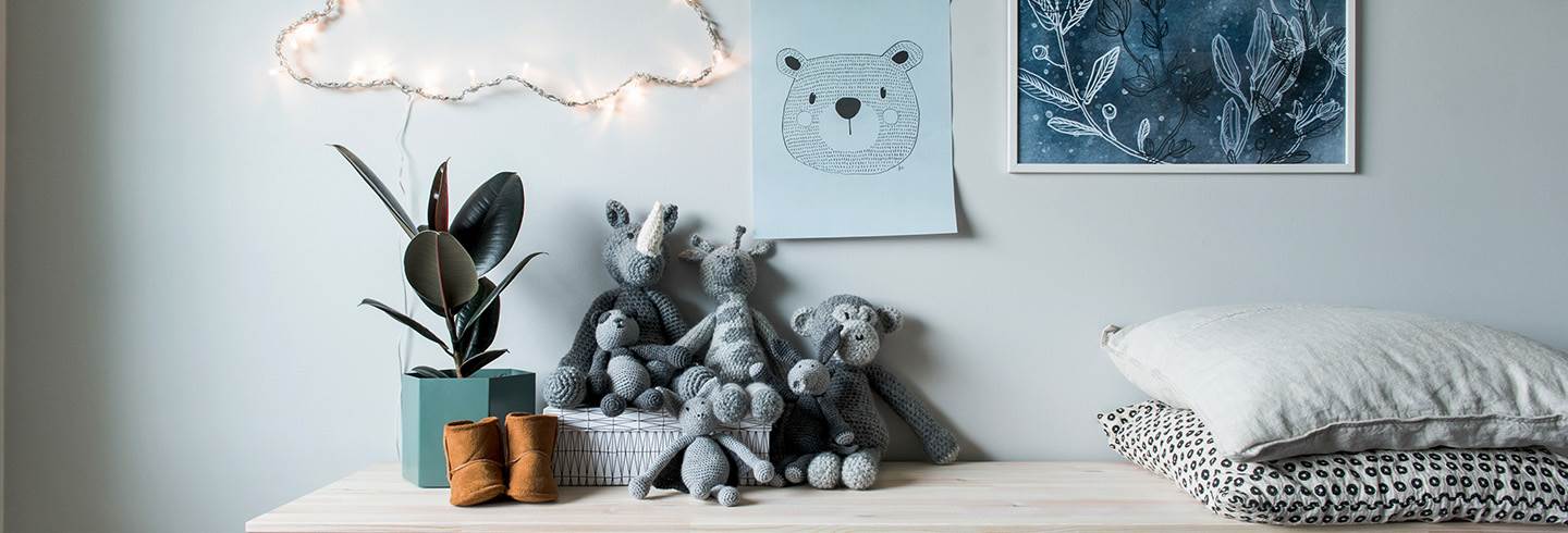 Crocheted teddies, pillows, plant and childrens shoes on dresser with posters over. Crocheted teddies, pillows, plant and childrens shoes on dresser with posters over.
