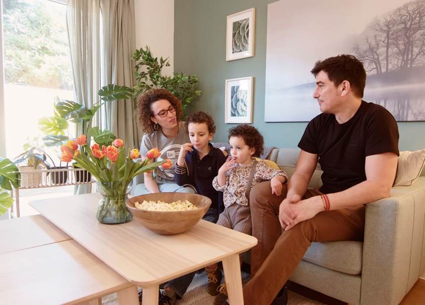 Family sat together on sofa laughing