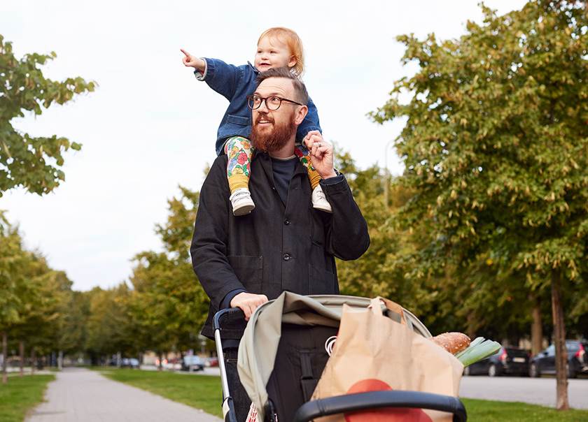 Father carries daugther on sholders and drives a pram.
