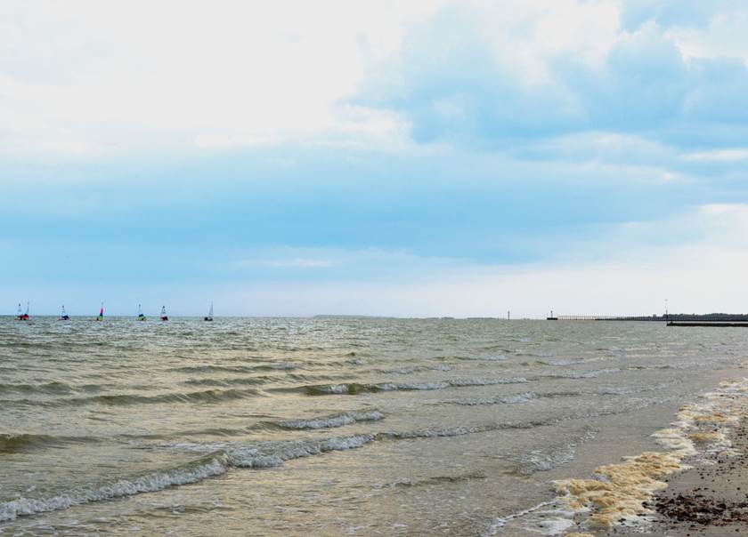 Beach with sailing boats on sea.