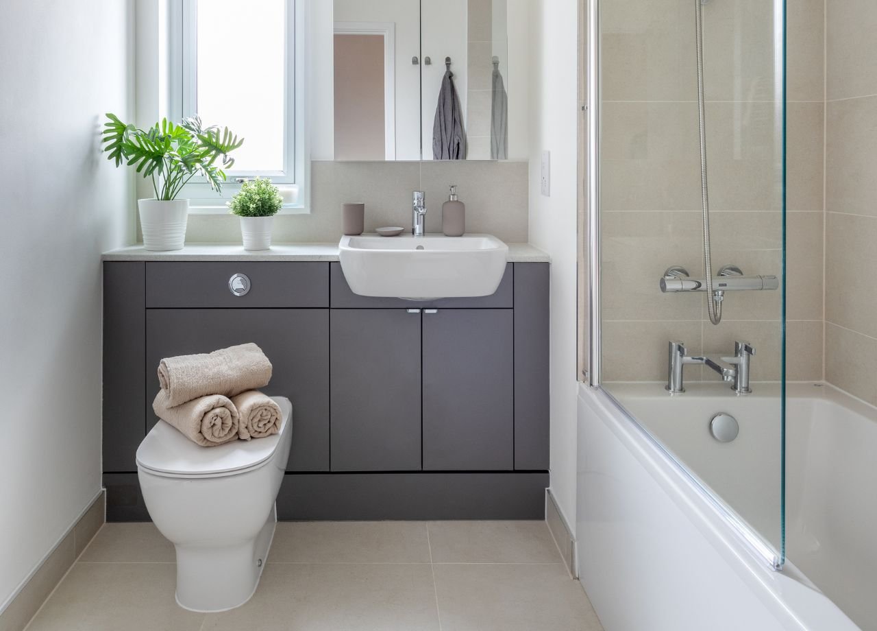 Bathroom with in-bath shower and grey cabinet.