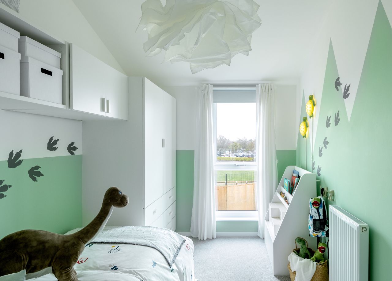 Single bedroom with walls in green and a window offering a view of the garden.