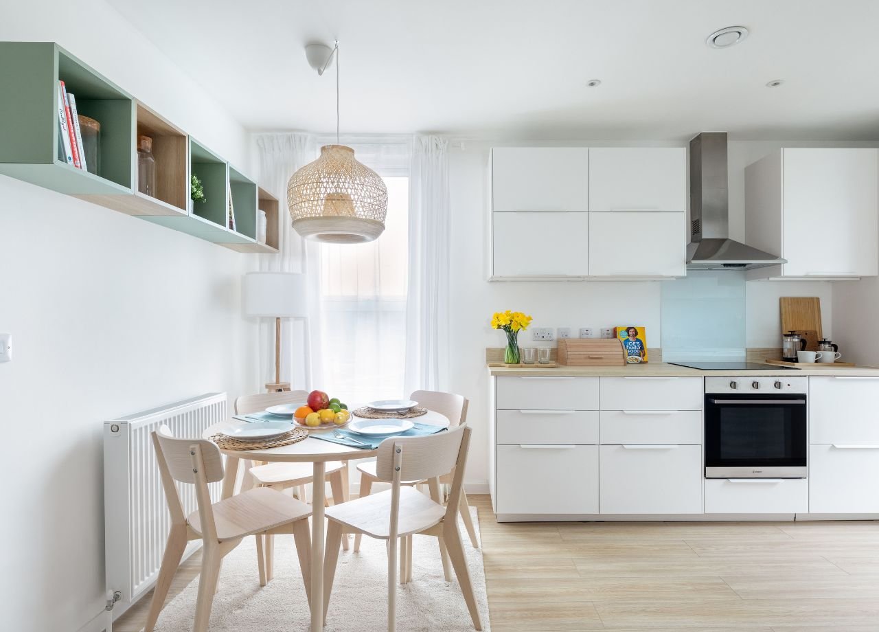 Internal kitchen/dining shot with white kitchen cabinets and wooden floor.