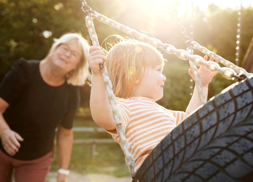 Elderly woman with little girl on a swing.